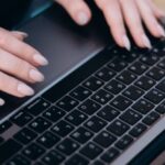 Tech Start-Ups - A person sitting on a bench with their hands on a laptop