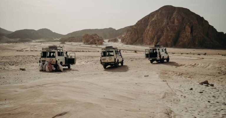 Autonomous Vehicles - Four jeeps are parked in the desert with mountains in the background