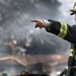 Natural Disasters - Fire Fighter Wearing Black and Yellow Uniform Pointing for Something
