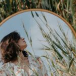 Creative Constraints - A woman in a field looking at a mirror