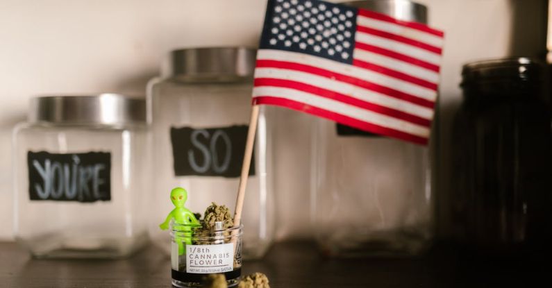 Extraterrestrial Life - US Flag and a Green Toy Alien Sticking from a Glass Jar with Marijuana