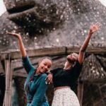 Budget-Friendly Travel - Women Posing while Standing Beside Animal Statue