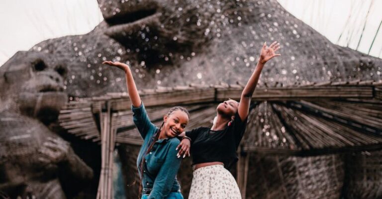 Budget-Friendly Travel - Women Posing while Standing Beside Animal Statue