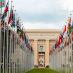 International Sanctions - From below of various flags on flagpoles located in green park in front of entrance to the UN headquarters in Geneva