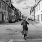 Sustainable Cities - Woman Riding Bike Crossing Street Intersection
