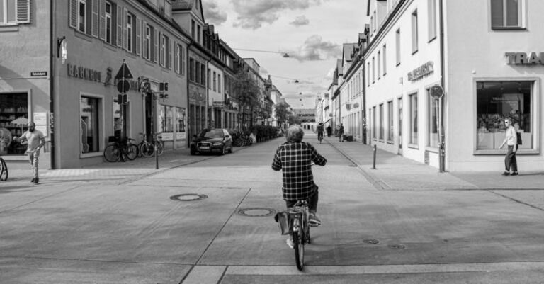 Sustainable Cities - Woman Riding Bike Crossing Street Intersection
